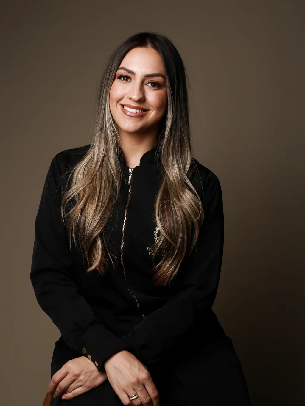 Dra. Letícia Bavaresco, fisioterapeuta, em retrato de jaleco sobre fundo neutro